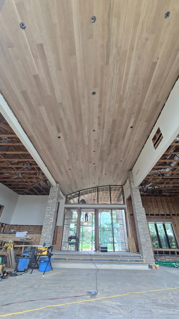 Warm white oak ceiling boards installed with controlled joints, consistent spacing, and clean architectural transitions.