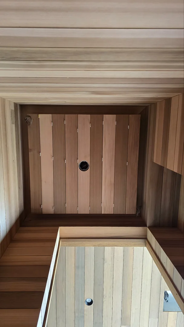 Wood ceiling boards and wall paneling meet around a recessed ceiling panel, with openings for recessed lights.
