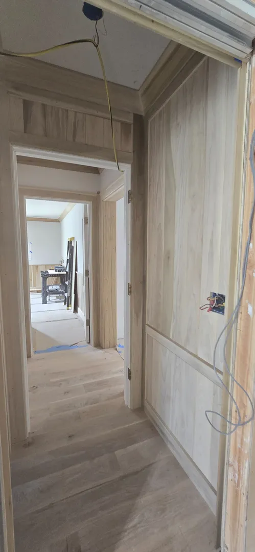 White oak doorway, wall panels, and ceiling boards aligned through a corridor.