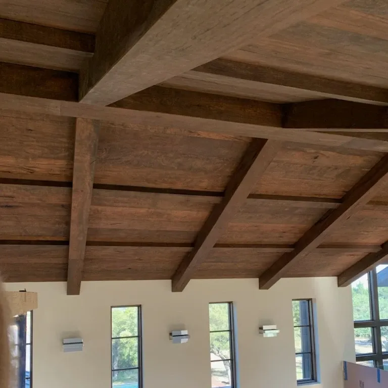 Close architectural view of stained wood beams framing precisely fitted ceiling panels.