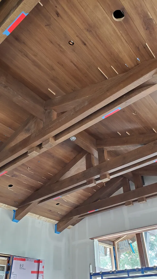 Exposed timber ceiling grid with fitted boards, lighting openings, and temporary alignment spacers.