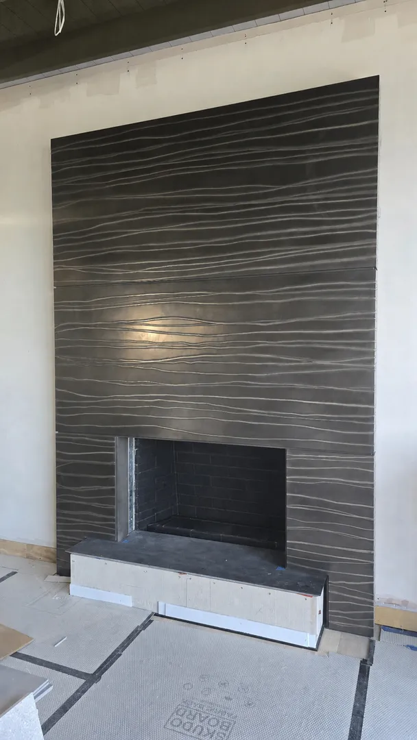 Dark stone fireplace surround and hearth during finish installation.