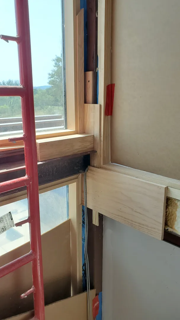 Close construction view of custom wood casing fitted at a tall window.