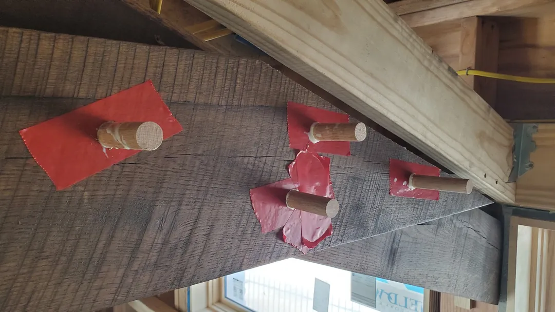 Exposed timber beam fitted with custom wood pegs during structural finish work.