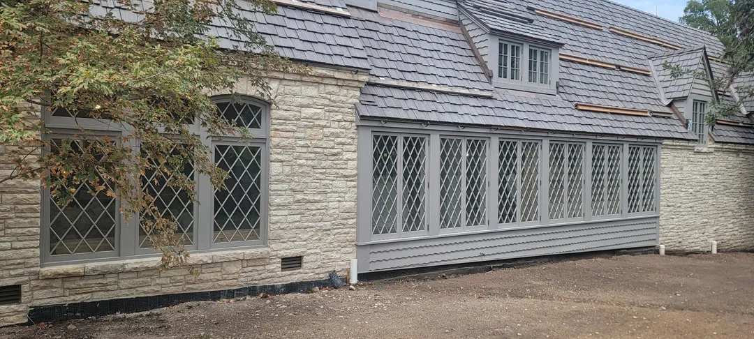 Diamond-pane window wall along the stone residence exterior.