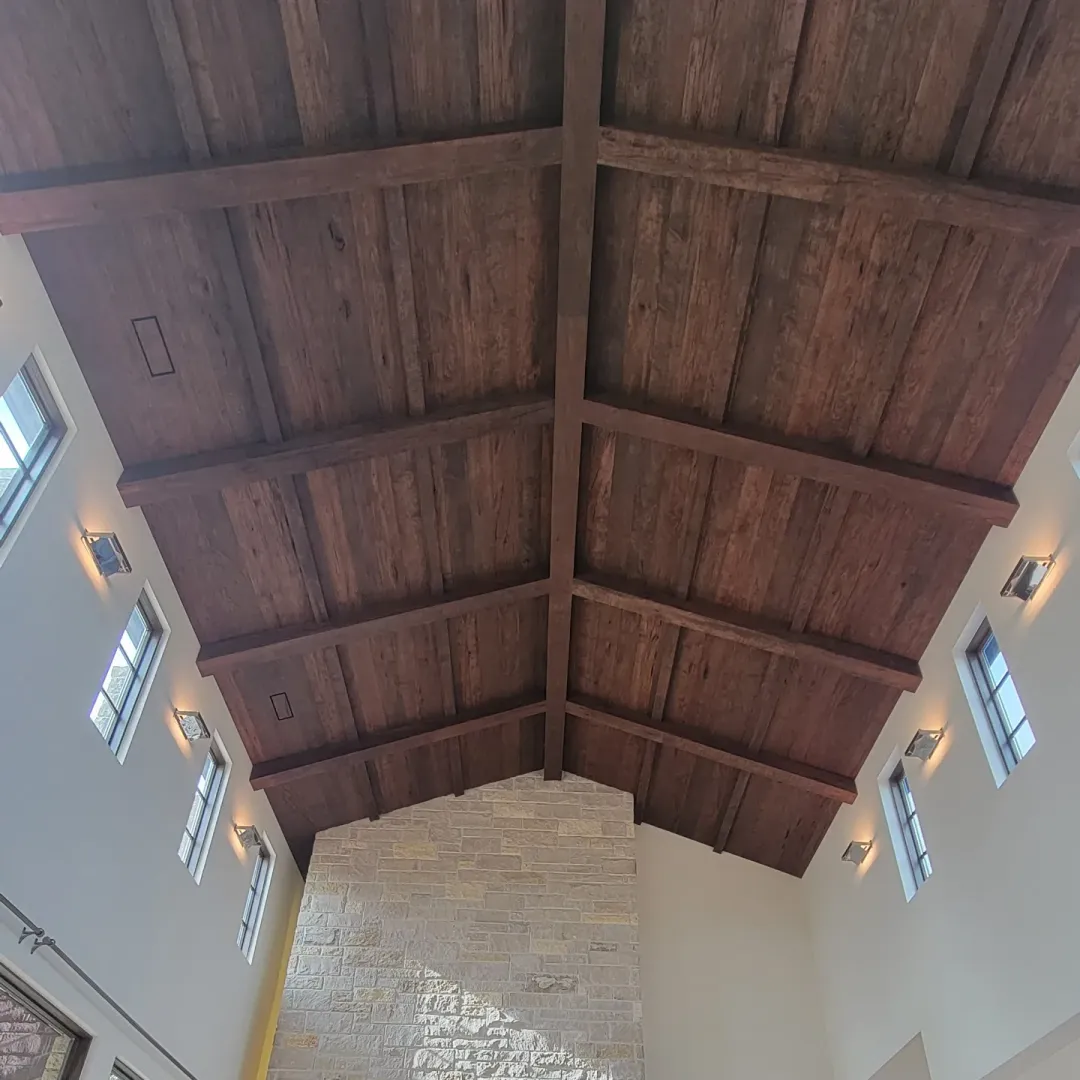 Finished vaulted ceiling with dark wood beam grid, paneled bays, and coordinated wall lighting.