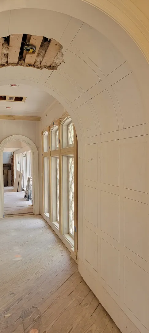 Curved paneled corridor and window wall during finish installation.